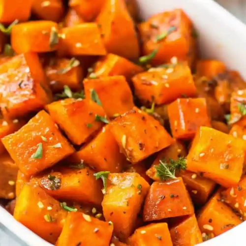 Close-up of roasted butternut squash cubes with herbs in a white dish