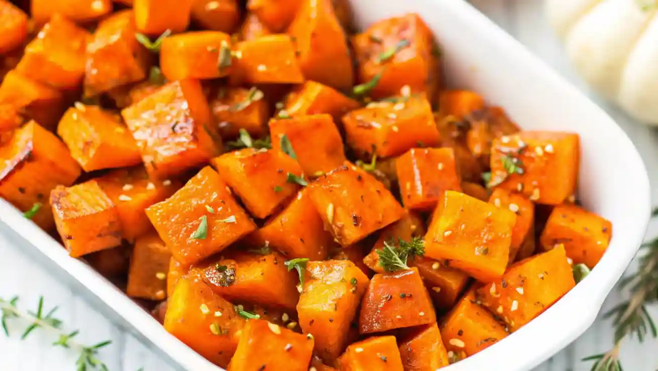 Close-up of roasted butternut squash cubes with herbs in a white dish