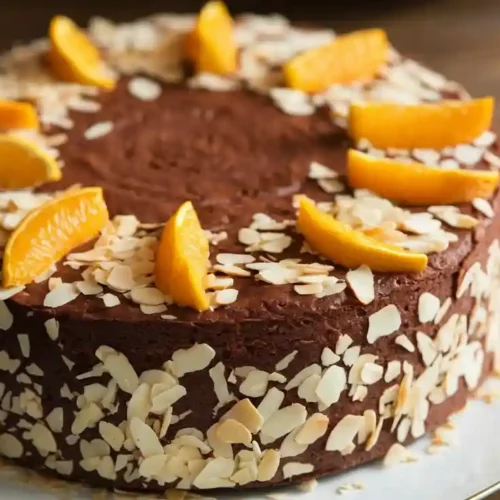 Prolific Oven Chocolate Orange Almond Cake recipe with orange and almond flakes on top.