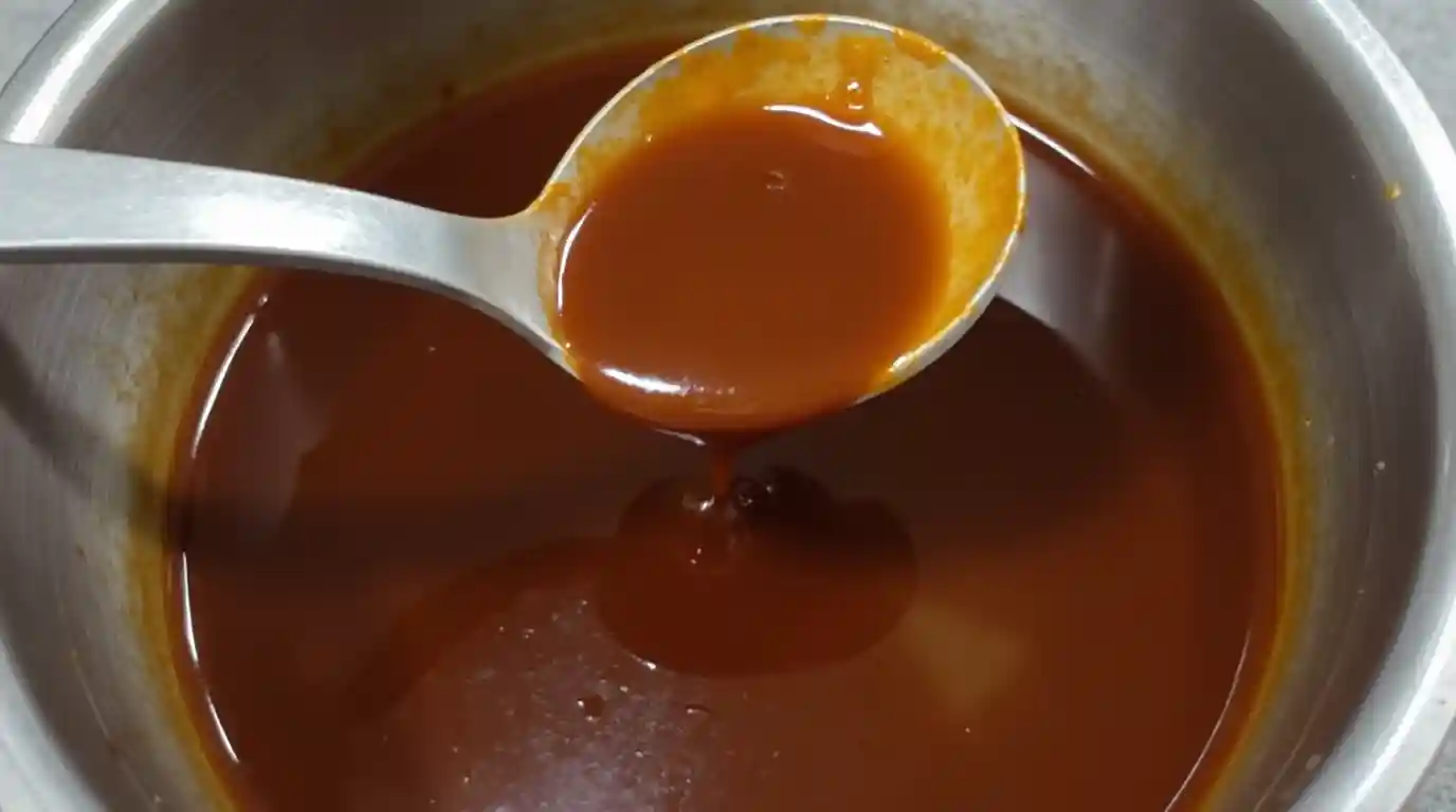 A pot of simmering golden demi-glace recipe with a rich, glossy texture.