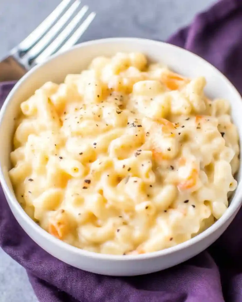Creamy homemade baked mac and cheese served in a white bowl with black pepper on top