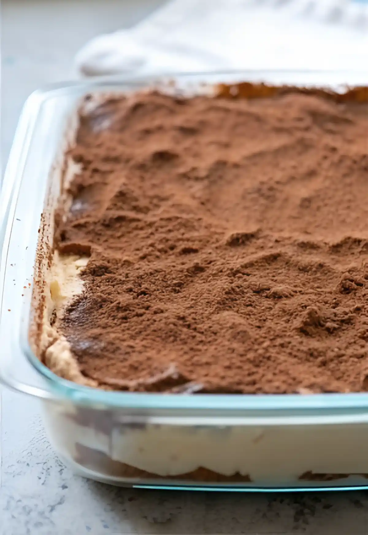 Glass dish of classic tiramisu topped with a generous dusting of cocoa powder