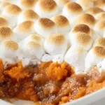 Sweet potato casserole topped with golden-brown toasted marshmallows in a white baking dish