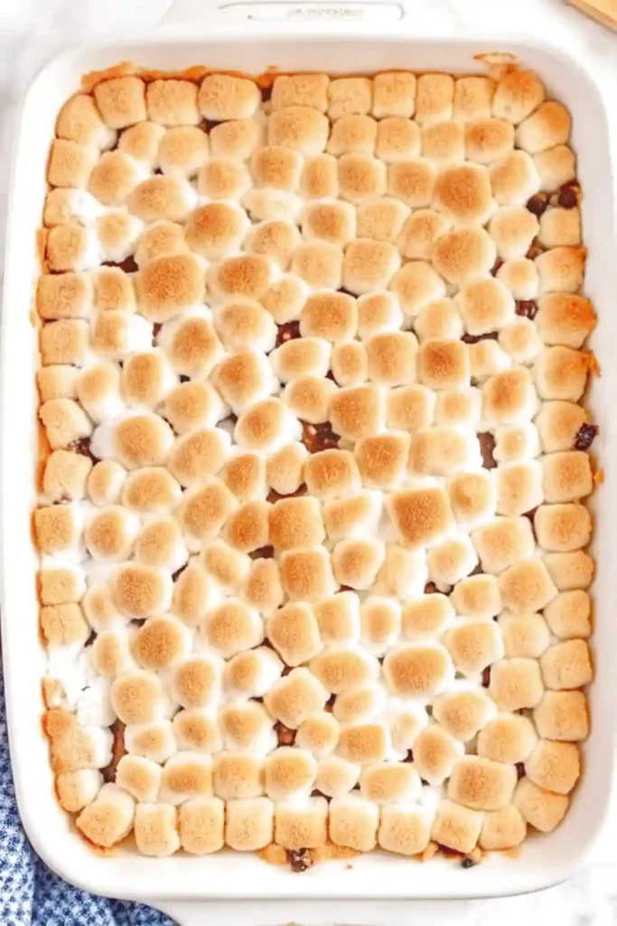 Top view of a sweet potato casserole in a white baking dish topped with evenly toasted mini marshmallows