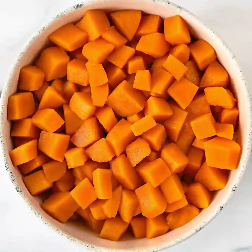 Bowl filled with evenly cubed, cooked sweet potatoes ready for mashing