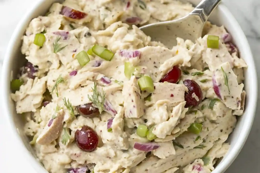 Bowl of creamy chicken salad with grapes, celery, dill, and red onion