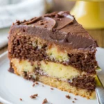 Slice of homemade marble cake with chocolate frosting on a white plate