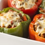 Baked stuffed bell peppers filled with beef, rice, and melted cheese in a white casserole dish