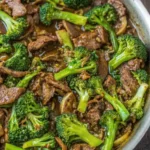 Beef and broccoli stir fry in a pan with tender beef strips and bright green broccoli in a glossy sauce.