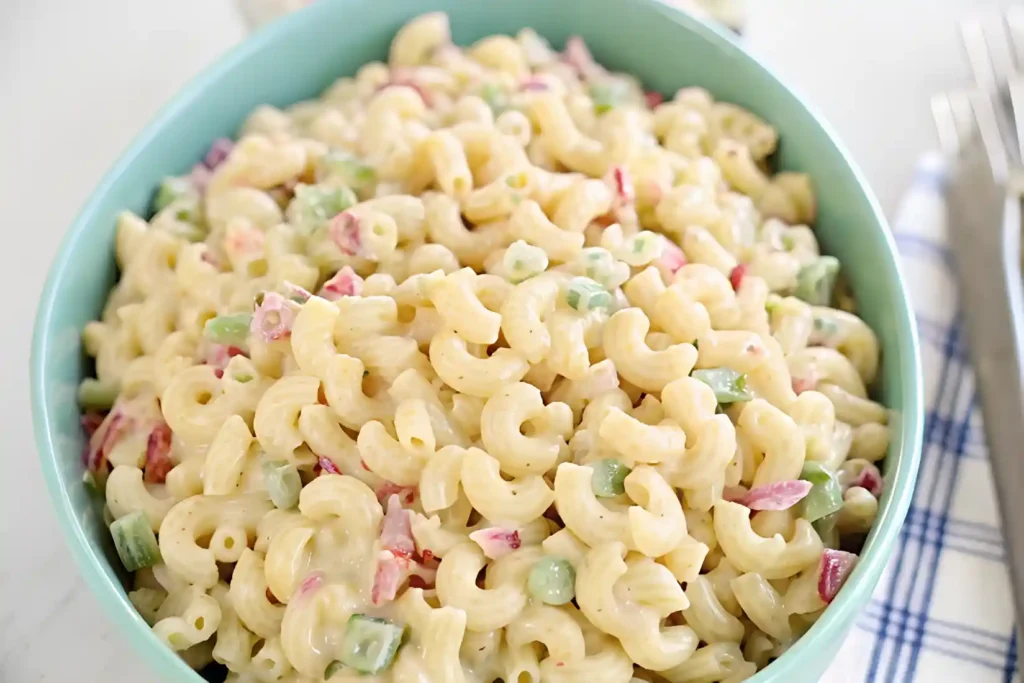 Bowl of creamy macaroni salad with chopped red and green bell peppers.