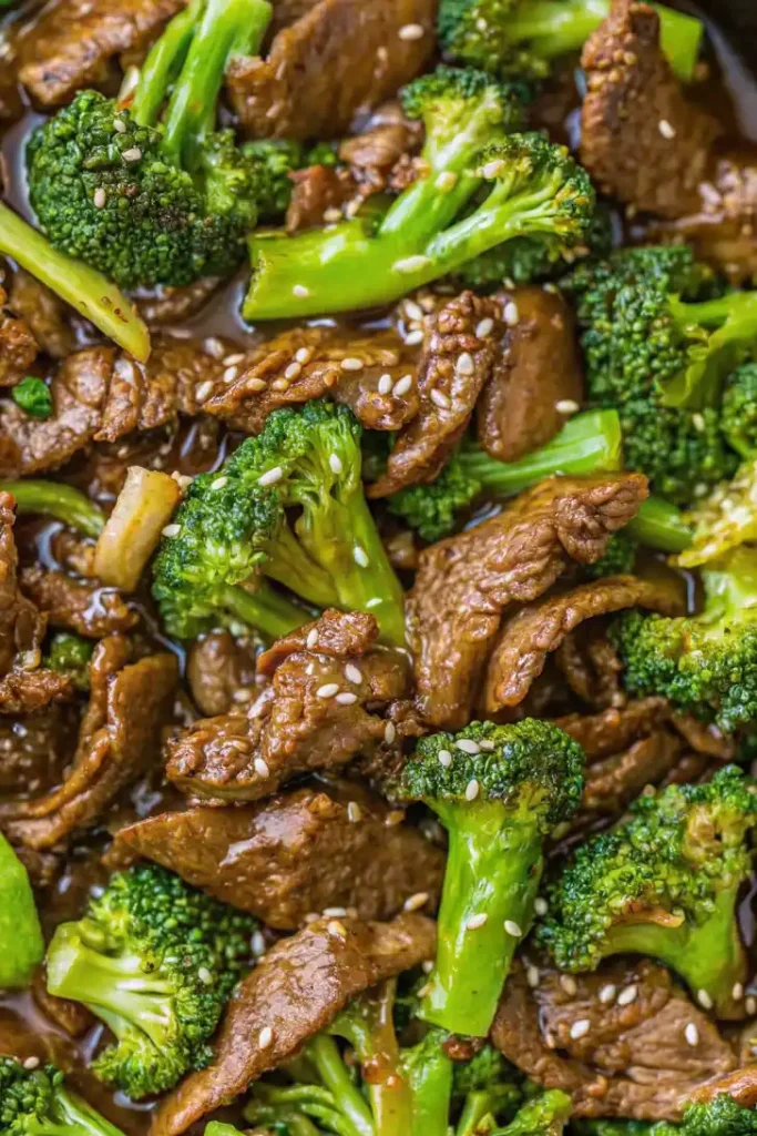 Close up of beef and broccoli stir fry with tender beef strips and bright green broccoli coated in a glossy sauce.