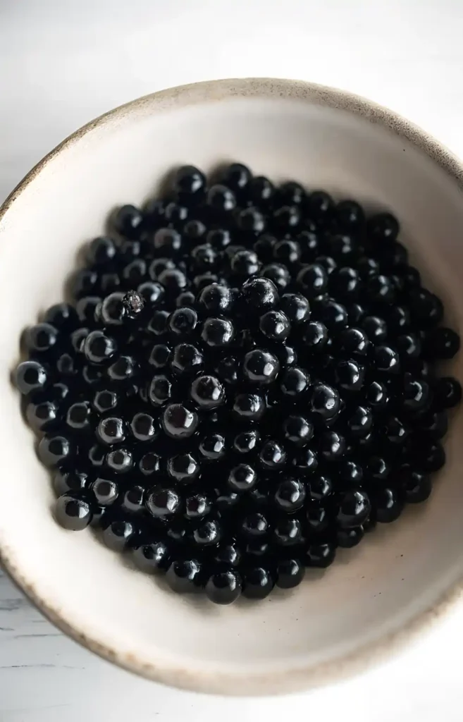 A bowl filled with shiny black tapioca pearls used for boba tea.
