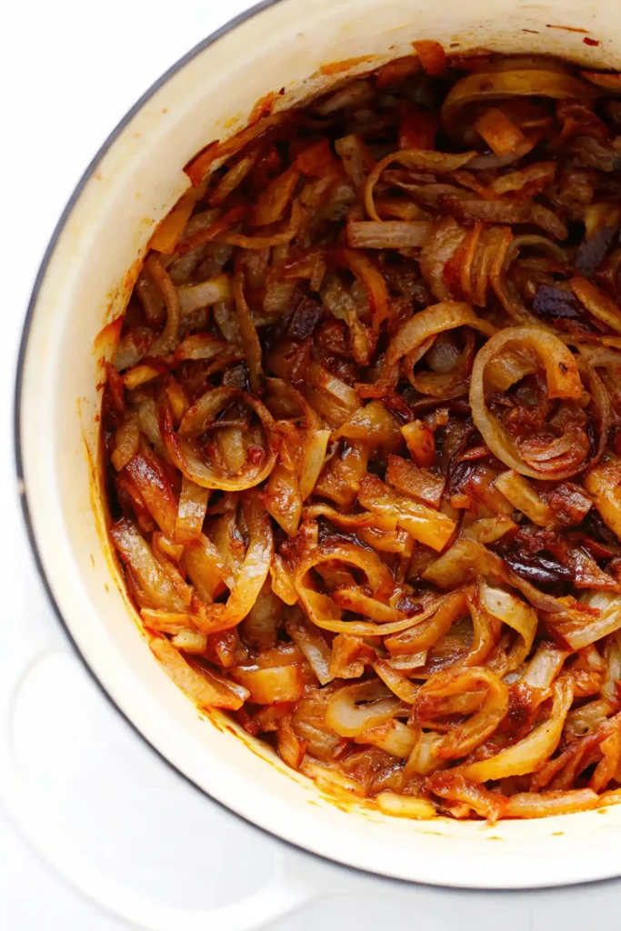Golden caramelized onions cooking in a white Dutch oven.