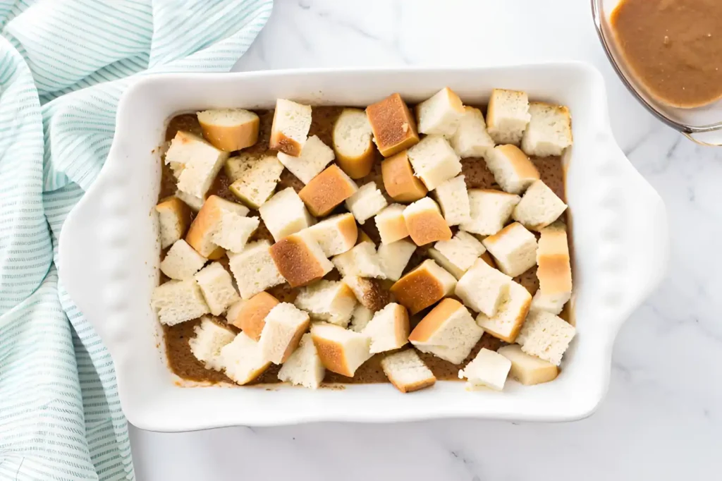 Unbaked French toast casserole with bread cubes soaking in cinnamon custard in a white baking dish.