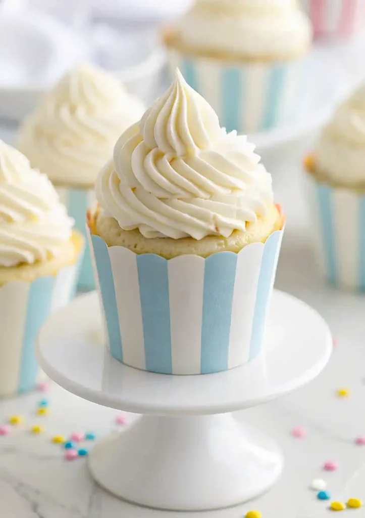 Vanilla cupcake with tall buttercream swirl in a blue striped wrapper