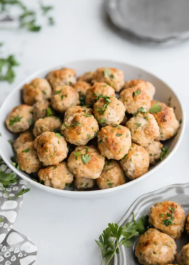 Healthy turkey meatballs in a white bowl garnished with fresh parsley