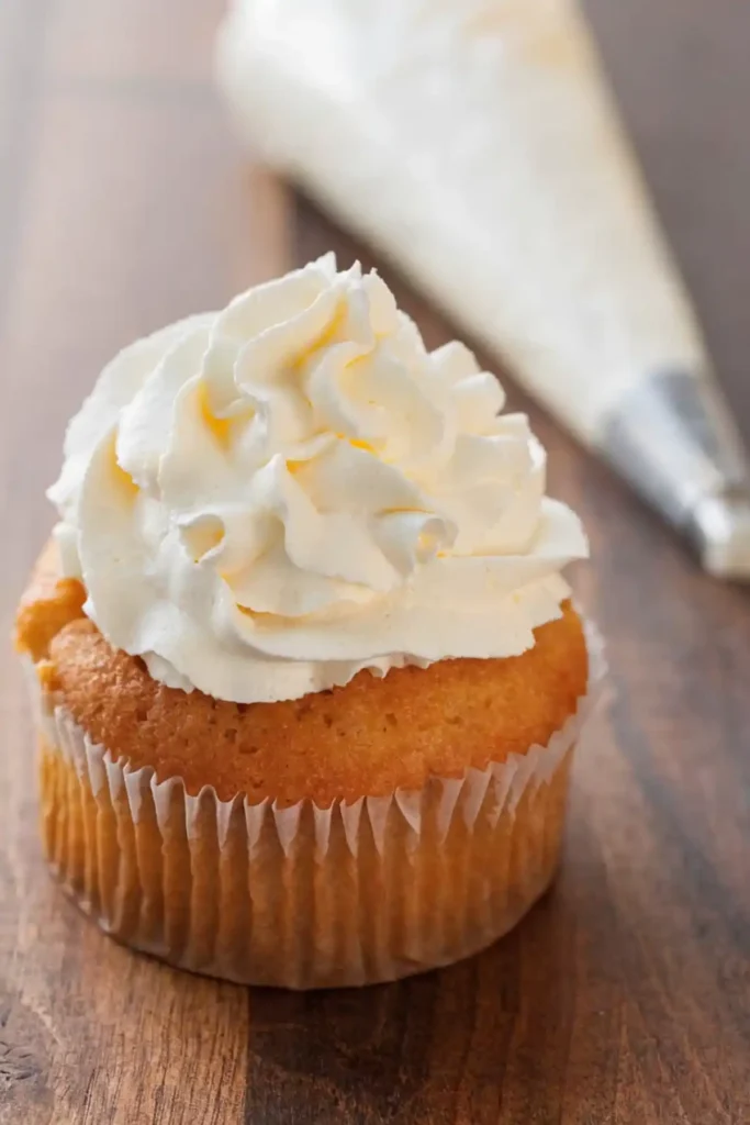 Vanilla cupcake topped with homemade whipped cream swirl