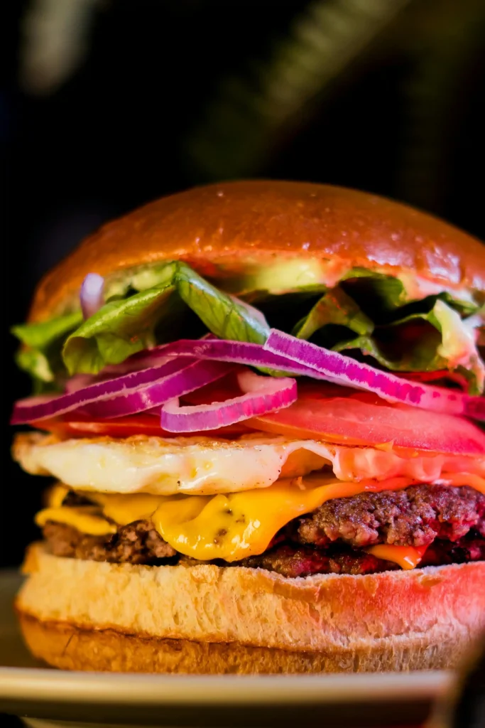 Homemade cheeseburger with Big Mac special sauce, melted cheddar, fried egg, lettuce, tomato, and red onion on a toasted bun.