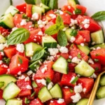 Fresh watermelon feta salad with cucumber, mint, and basil in a white bowl
