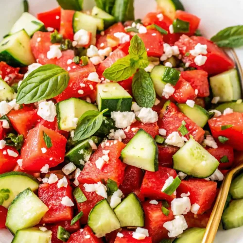 Fresh watermelon feta salad with cucumber, mint, and basil in a white bowl