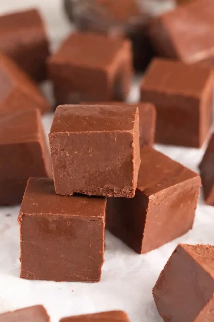 Stacked chocolate fudge cubes made with three ingredients, showing smooth creamy texture and rich homemade chocolate squares.