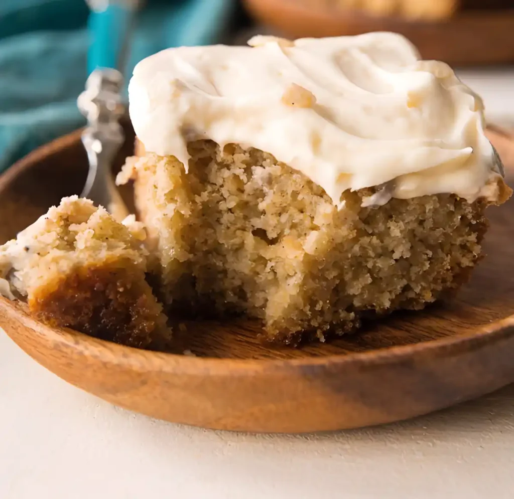 Easy banana cake slice with cream cheese frosting and bite taken