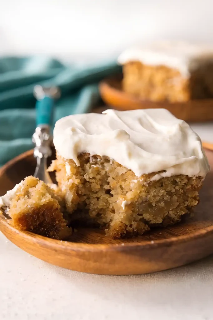 Easy banana cake slice with cream cheese frosting on wooden plate
