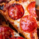 Homemade pepperoni pizza slice with melted mozzarella cheese and crispy crust being lifted by hand.