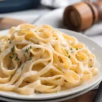 Creamy Fettuccine Alfredo pasta served on a white plate with parmesan and parsley garnish