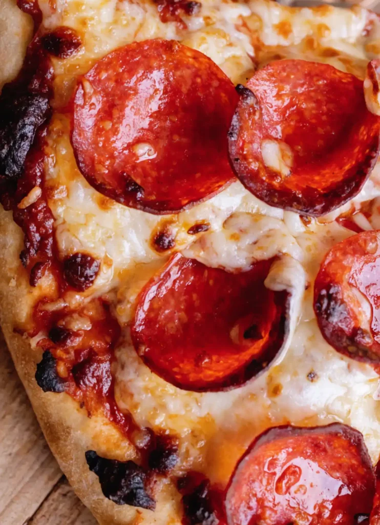Close up of homemade pepperoni pizza with melted mozzarella cheese, crispy pepperoni slices, and golden crust.