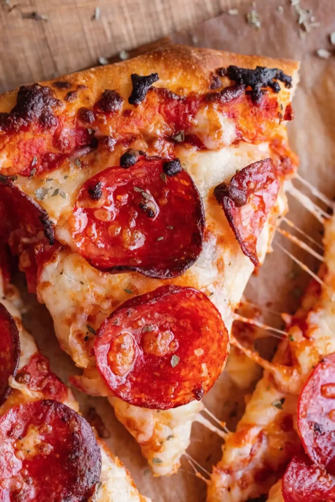 Homemade pepperoni pizza slice with melted mozzarella cheese and crispy pepperoni on a golden crust.