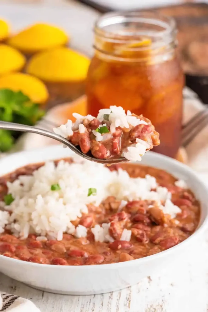 Louisiana red beans and rice with creamy beans and white rice served in a bowl with a spoon lifting a bite