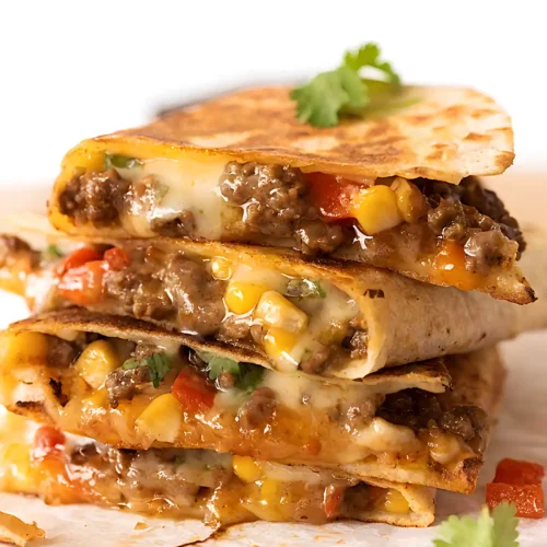 Crispy beef quesadilla stacked with melted cheese, corn, and bell peppers on a wooden board