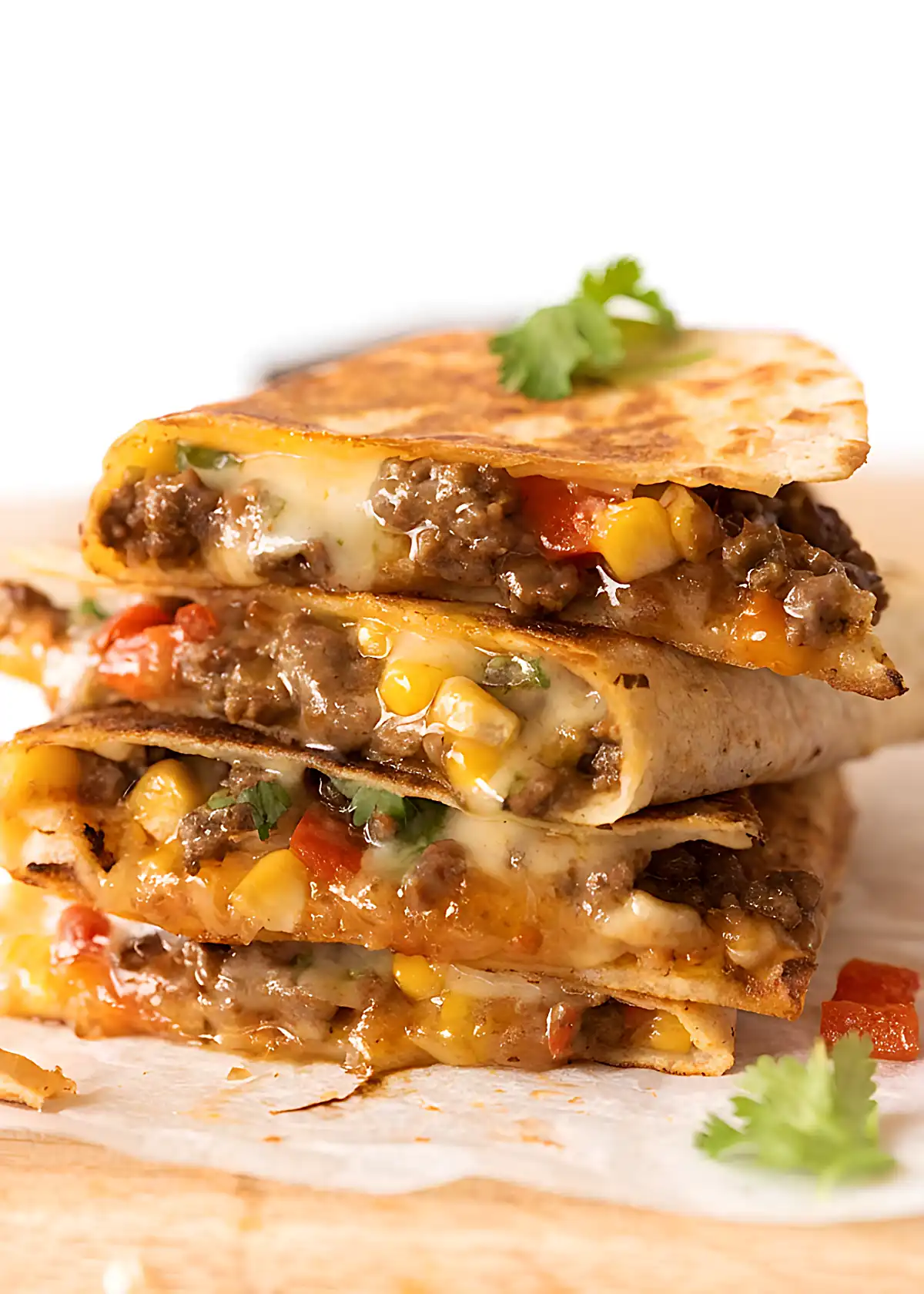 Crispy beef quesadilla stacked with melted cheese, corn, and bell peppers on a wooden board