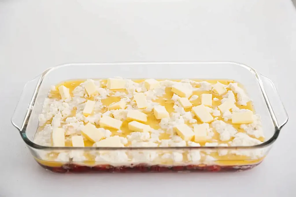 easy dump cake recipe before baking with cake mix and butter in glass dish