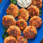 Crispy salmon patties on a blue plate served with creamy tartar sauce and fresh parsley