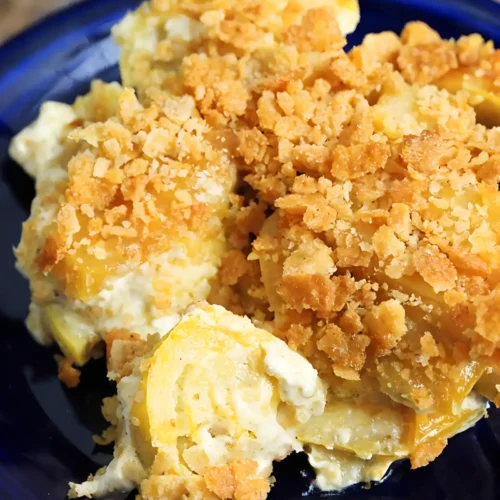 Squash casserole with creamy cheese filling and crispy golden cracker topping served on a blue plate
