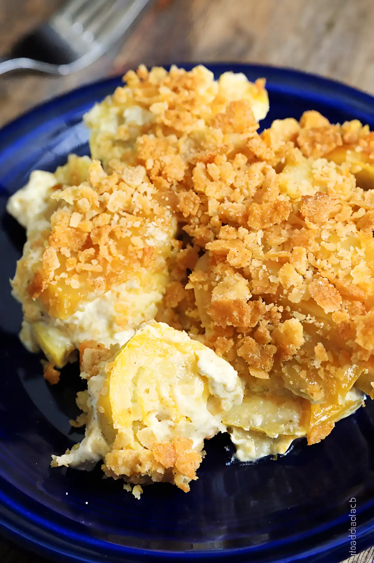Squash casserole with creamy cheese filling and crispy golden cracker topping served on a blue plate