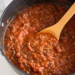 spaghetti meat sauce simmering in pan with wooden spoon
