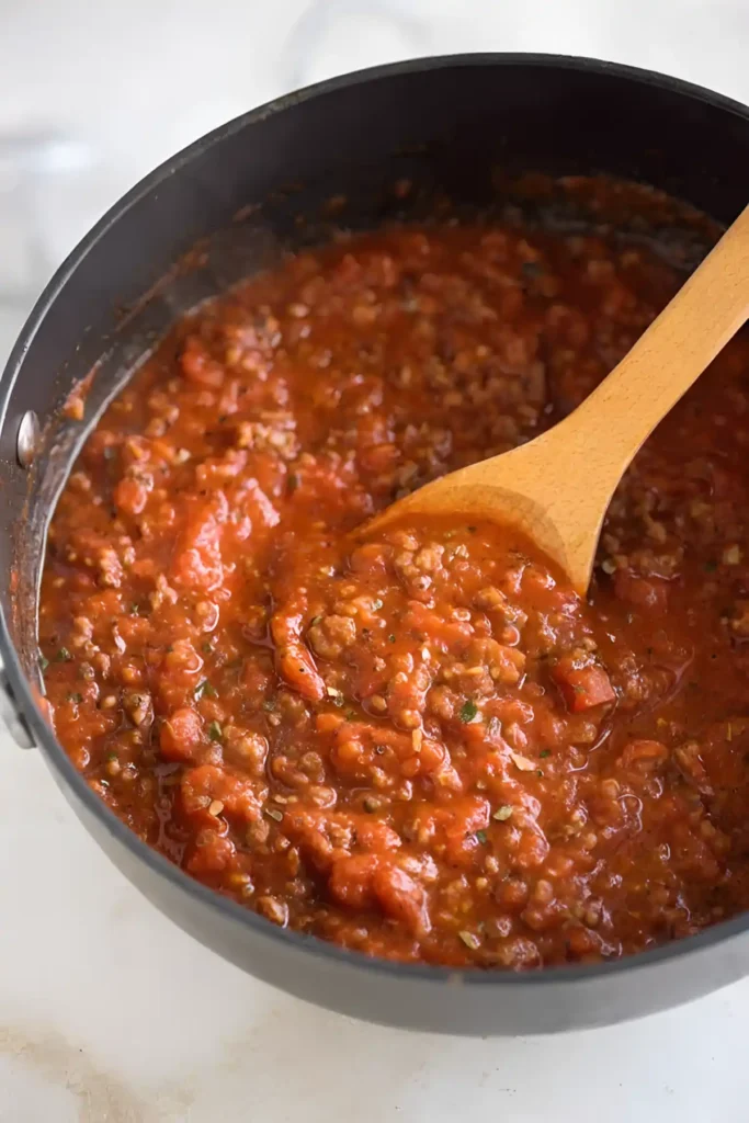 spaghetti meat sauce simmering in pan with wooden spoon