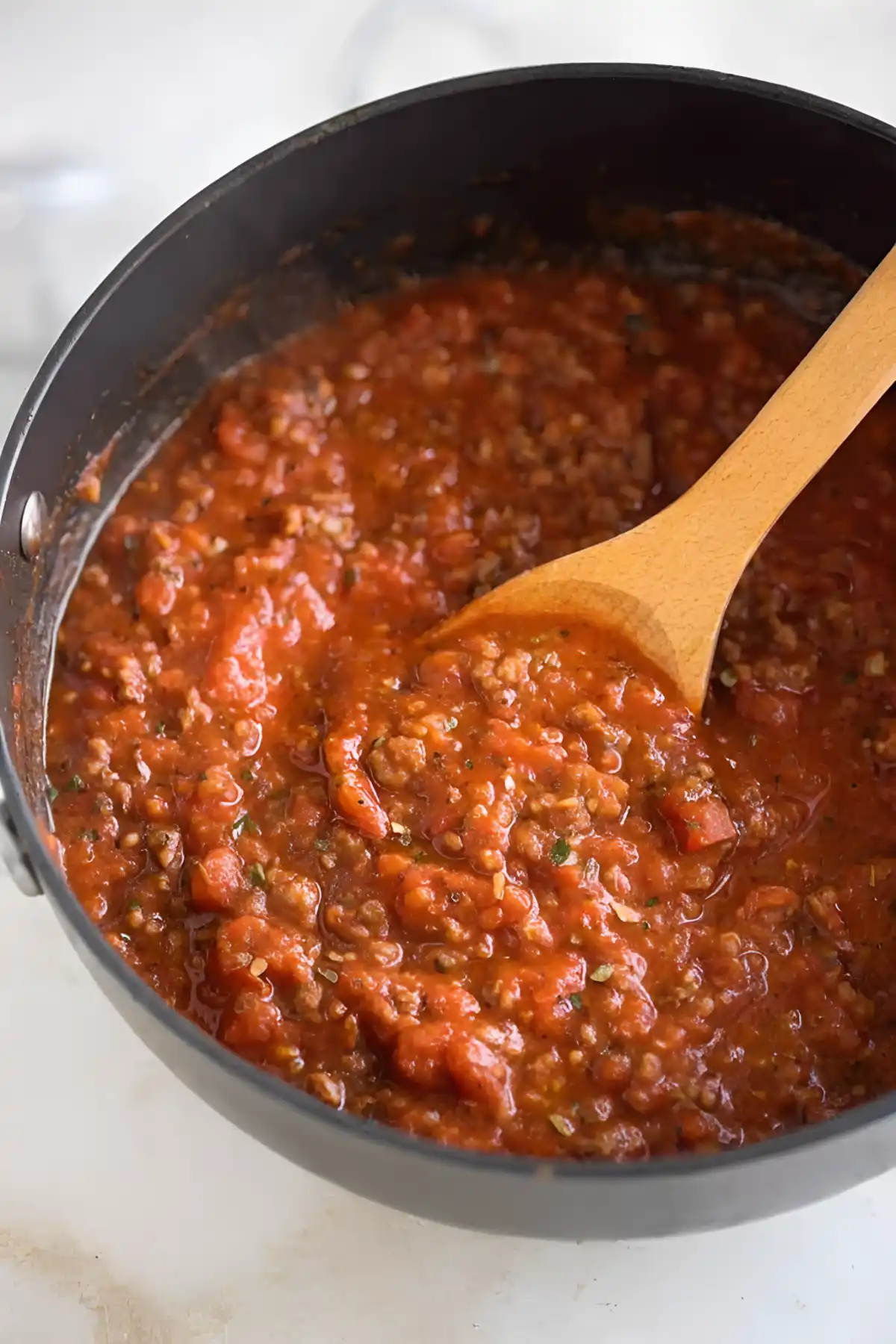 spaghetti meat sauce simmering in pan with wooden spoon