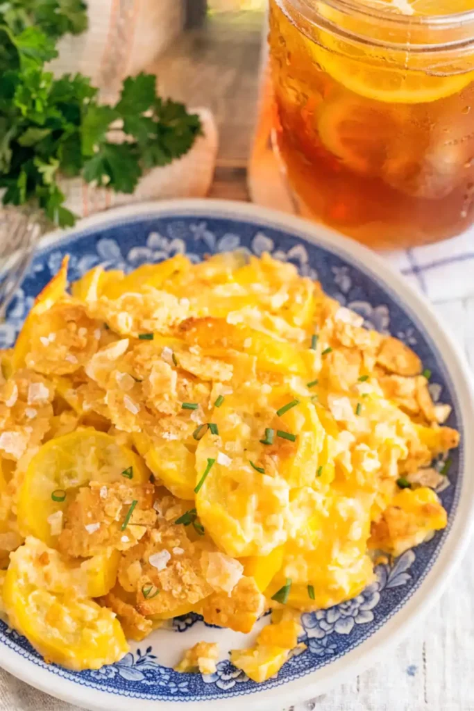 Southern squash casserole with creamy cheese, yellow squash slices, and crispy cracker topping served with iced tea