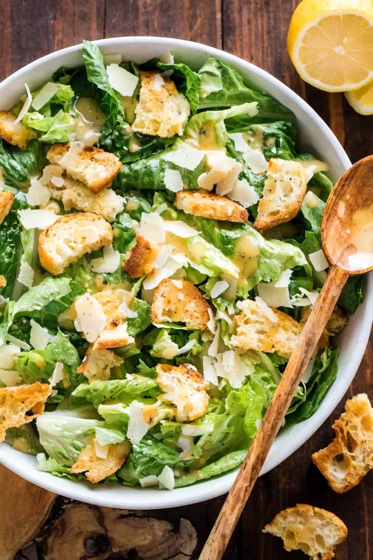 Caesar salad recipe with romaine lettuce, crispy croutons, shaved parmesan, and creamy dressing in a white bowl