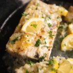 Pan-seared mahi mahi fillet with lemon garlic butter sauce, topped with fresh parsley and a lemon slice in a skillet.