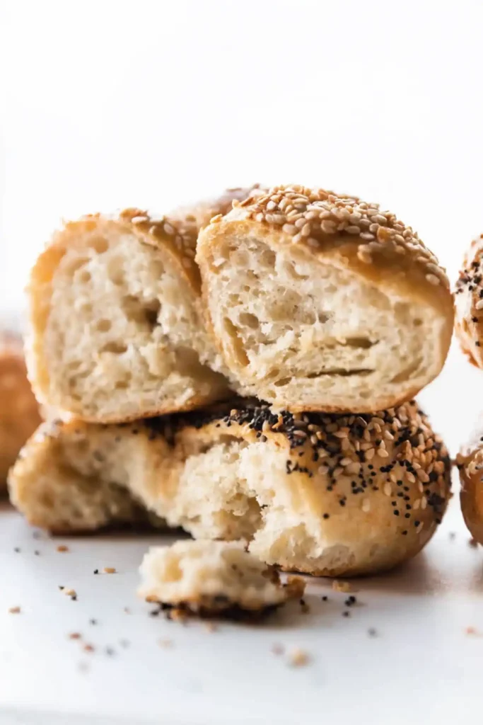 Close up of sliced homemade bagels stacked to show a soft chewy interior with sesame and everything seasoning toppings