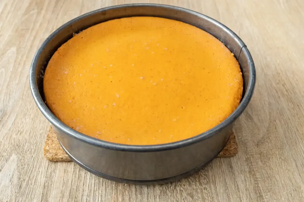 Baked pumpkin cheesecake in a springform pan on a wooden table