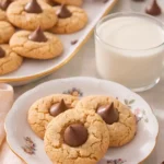 Peanut butter blossom cookies with chocolate kisses on a plate served with a glass of milk