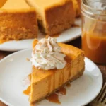 Pumpkin cheesecake slice with whipped cream and caramel drizzle on a white plate