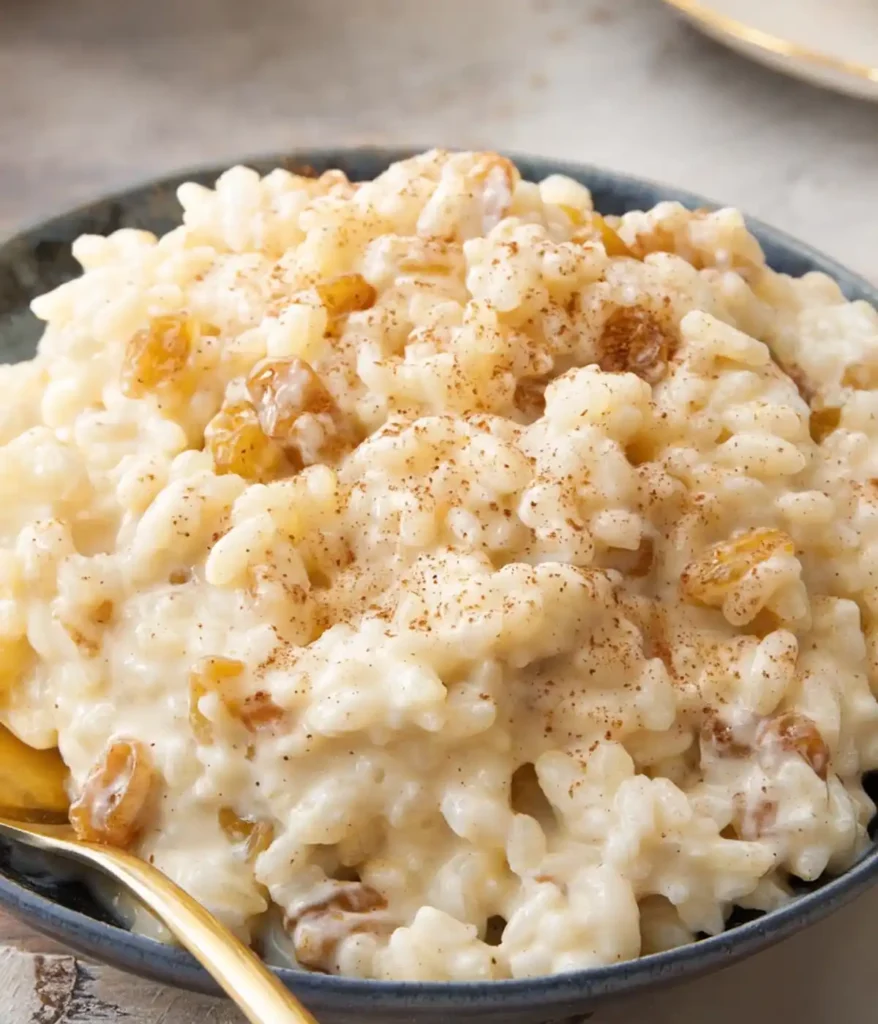 Creamy rice pudding with raisins and cinnamon in a bowl with a spoon