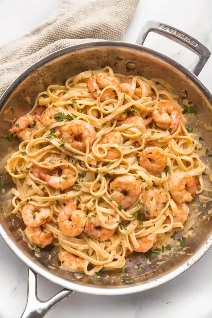 Creamy shrimp pasta in a skillet with linguine, garlic sauce, and fresh parsley garnish